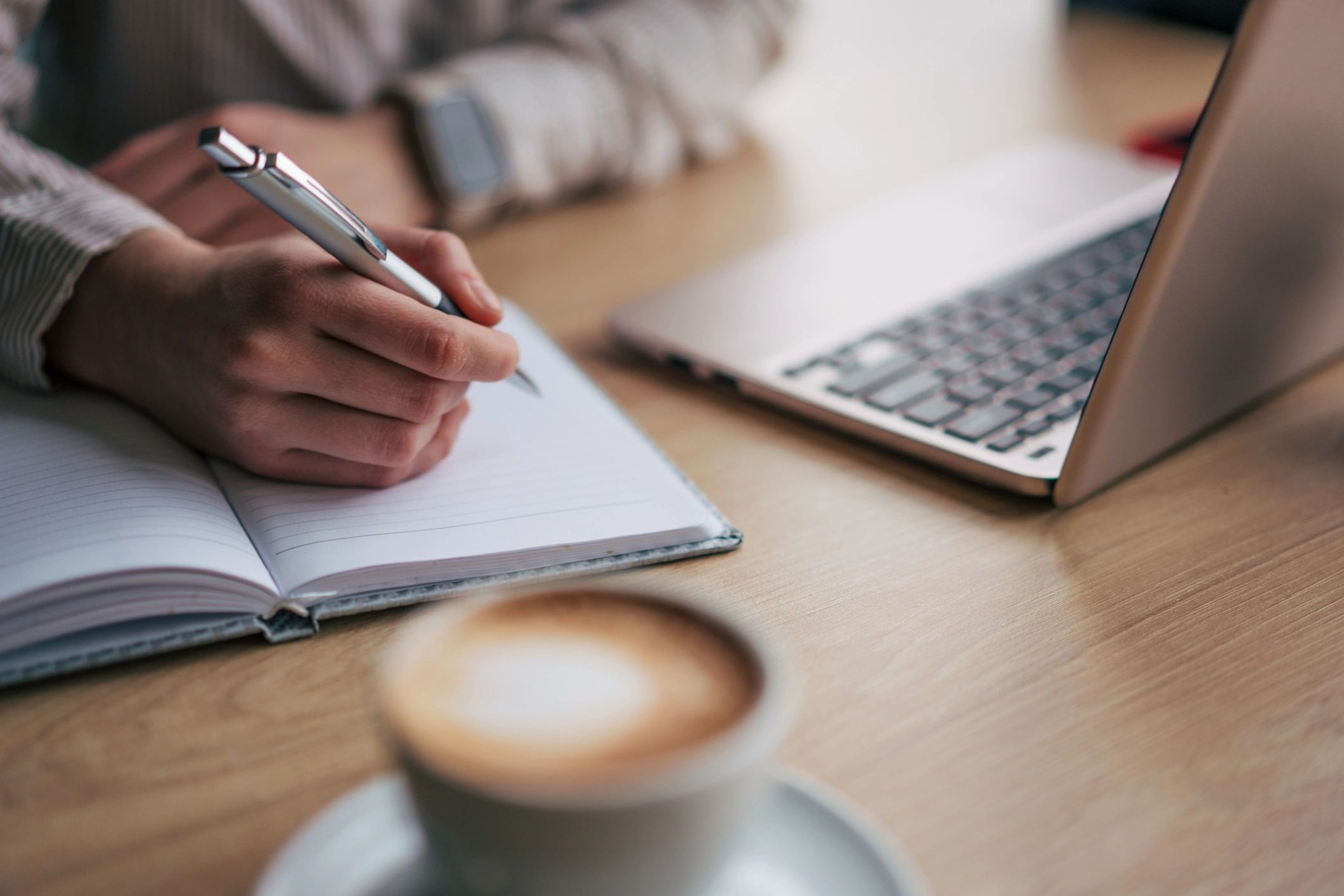 Handwriting notes next to a laptop while drafting a review